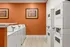 Bright, modern laundry room with vibrant orange walls, sleek washing machines, and contemporary artwork.