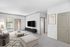 Modern living room with stylish d&eacute;cor, featuring a sleek TV setup, abstract wall art, and large windows for natural light.
