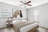 Bright and inviting bedroom with modern decor, featuring a cozy queen-sized bed, stylish ceiling fan, and abstract wall art for a touch of elegance.