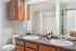 Modern bathroom featuring dual sinks, elegant wooden cabinetry, and sleek quartz countertops with stylish decor accents.