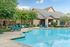 Inviting apartment complex pool area with refreshing blue water, surrounded by lush greenery and ample lounging space.