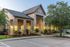 Charming apartment exterior with a modern stone facade, inviting porch, and well-kept landscaping illuminated by warm lights.