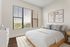 Elegant bedroom with modern decor featuring a cozy bed, large window with a scenic view, and minimalist artwork on the wall.
