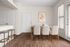 Bright dining area with elegant wooden table, plush chairs, and artistic wall decor, complemented by natural wood flooring and abundant light.