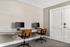 Modern home office space featuring dual workstations with sleek computers and stylish wooden chairs, perfect for productivity.