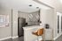 Modern kitchen with sleek gray cabinets, stylish pendant lights, and stainless steel appliances, featuring a cozy breakfast bar with a chic wooden stool.
