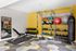 Vibrant home gym with modern equipment, including free weights, kettlebells, workout bench, and a punching bag against a bright yellow accent wall.