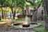 Charming apartment exterior with a serene fountain surrounded by lush greenery and mature trees.