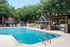 Inviting outdoor pool area with a grill station, pergola, and lush trees providing a serene retreat.