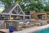 Charming outdoor patio with elegant stone seating, vibrant blue planters, a cozy fire pit, and a pool, perfect for relaxation.