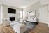 Bright and spacious living room with elegant white furniture, hardwood flooring, and a cozy fireplace.