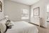 Bright and airy bedroom featuring elegant white decor, plush bedding, and a stylish dresser, complemented by natural light from a large window.
