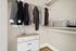 Elegant walk-in closet with neatly organized clothes, stylish baskets, and a modern dresser, perfect for maximizing storage space.