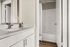 Modern bathroom with sleek white vanity, stylish fixtures, and a cozy shower area.