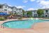 Inviting apartment complex with modern amenities, featuring a sparkling outdoor pool surrounded by relaxing lounge chairs and lush landscaping.