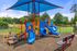Vibrant playground with colorful slides and climbing areas under a blue canopy, perfect for outdoor fun.