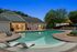 Charming apartment complex with a serene pool, inviting lounge chairs, and lush landscaping for relaxing evenings.