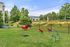Charming outdoor dog park with playful red tunnel, agility equipment, and lush greenery, perfect for active pet owners.