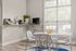 Bright dining area with modern white chairs, a stylish round table, and a cozy coffee nook, perfect for mornings.