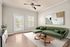 Elegant living room with a modern green sofa, abstract art, and natural light streaming through a glass door opening to a serene balcony.