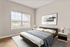 Elegant bedroom with a stylish bed, cozy side tables, and large window offering natural light and serene views.