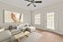 Bright and cozy living room with a stylish beige sectional sofa, modern ceiling fan, and large abstract wall art, inviting natural light through elegant blinds and French doors.