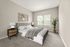 Serene bedroom with plush carpeting, stylish decor, and a large window inviting natural light.