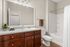 Elegant bathroom featuring a modern vanity with dark wood cabinets, a spacious mirror, and a tranquil ambiance.