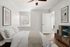 Inviting bedroom with cozy white bedding, elegant artwork, and sleek wooden flooring, exuding modern tranquility.