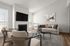 Modern living room with cozy beige sofas, stylish armchairs, and abstract art, featuring a fireplace and large flat-screen TV for ultimate comfort.