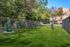 Charming pet-friendly garden space with lush greenery, fenced area, and cozy bench seating, perfect for relaxation.