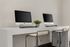 Modern home office setup with sleek computers and stylish seating, ideal for productive workdays.