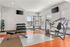Bright and inviting gym space featuring modern exercise equipment, free weights, and a bench, designed for fitness enthusiasts.