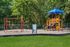 Inviting playground with vibrant slides, swings, and climbing structures, surrounded by lush greenery.