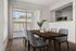 Bright dining area with elegant wood table and modern chairs, featuring floor-to-ceiling windows and a stylish open kitchen.