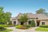 Charming suburban home with elegant stone facade, lush landscaped garden, and inviting walkway.
