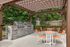 Charming outdoor picnic area with sleek stone grills and vibrant orange seating under a stylish pergola.
