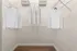 Spacious walk-in closet with sleek wooden floors and an organized wire shelving system, showcasing ample storage with hanging shirts and folded clothes.