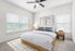Bright and stylish bedroom featuring a cozy bed with modern art on the wall, elegant blinds, and soft lighting.