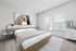 Bright and inviting modern bedroom with cozy furnishings, featuring a large window that floods the space with natural light.