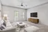 Bright and airy living room featuring modern decor, a comfortable sofa, chic patterned cushions, and a wall-mounted TV.