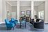 Modern and inviting office lounge with sleek blue chairs, plush black sofa, and a contemporary work area.