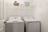 Contemporary laundry room with high-efficiency washer and dryer, featuring sleek shelving for organized storage.