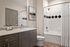 Elegant bathroom with modern finishes, featuring a sleek vanity, large mirror, and a stylishly tiled shower with geometric accents.