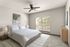 Bright and cozy bedroom featuring a plush bed with crisp white linens, stylish decor, and natural light streaming through large windows.