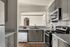 Modern kitchen with sleek gray cabinets, stainless steel appliances, and a spacious granite countertop featuring a bowl of vibrant red apples.