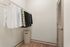 Spacious walk-in closet featuring stylish suits and blouses, with elegant wood flooring and ample storage space.