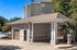Charming apartment complex with an elegant portico and car wash station, surrounded by lush greenery and clear blue skies.