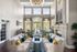 Luxurious living room with high ceilings, elegant fireplace, and bright, airy windows, featuring stylish sofas and chic decor.
