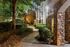 Charming apartment exterior with a stone facade and lush landscaped walkway, illuminated beautifully in the evening light.